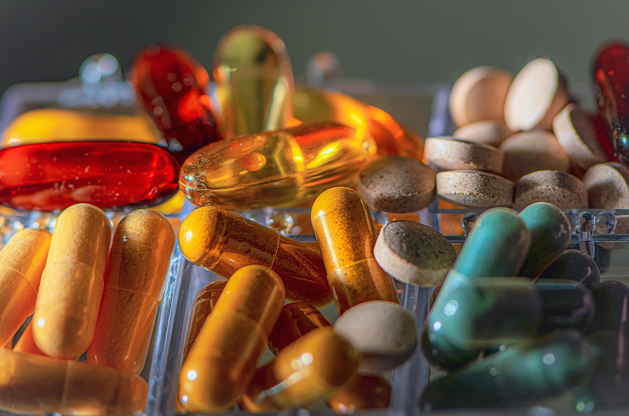 A close-up image of scattered red yellow and colorful pills on a neutral background.